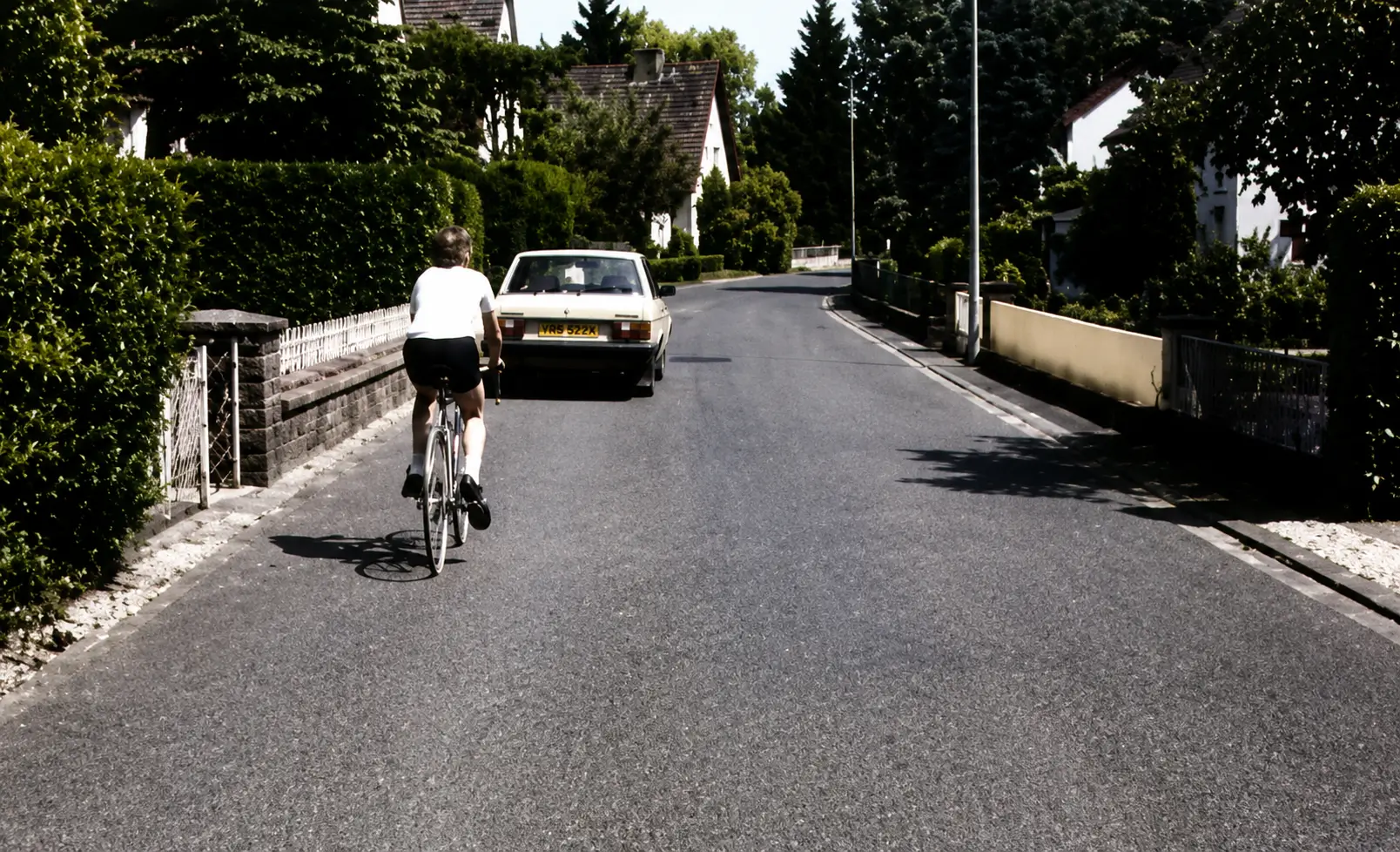 Cyclist and car on narrow road with parked car