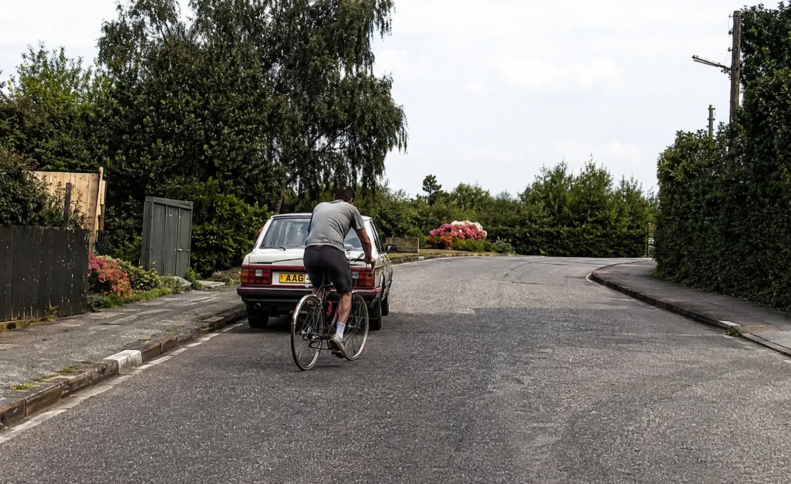 Car passing cyclist and stationary vehicle