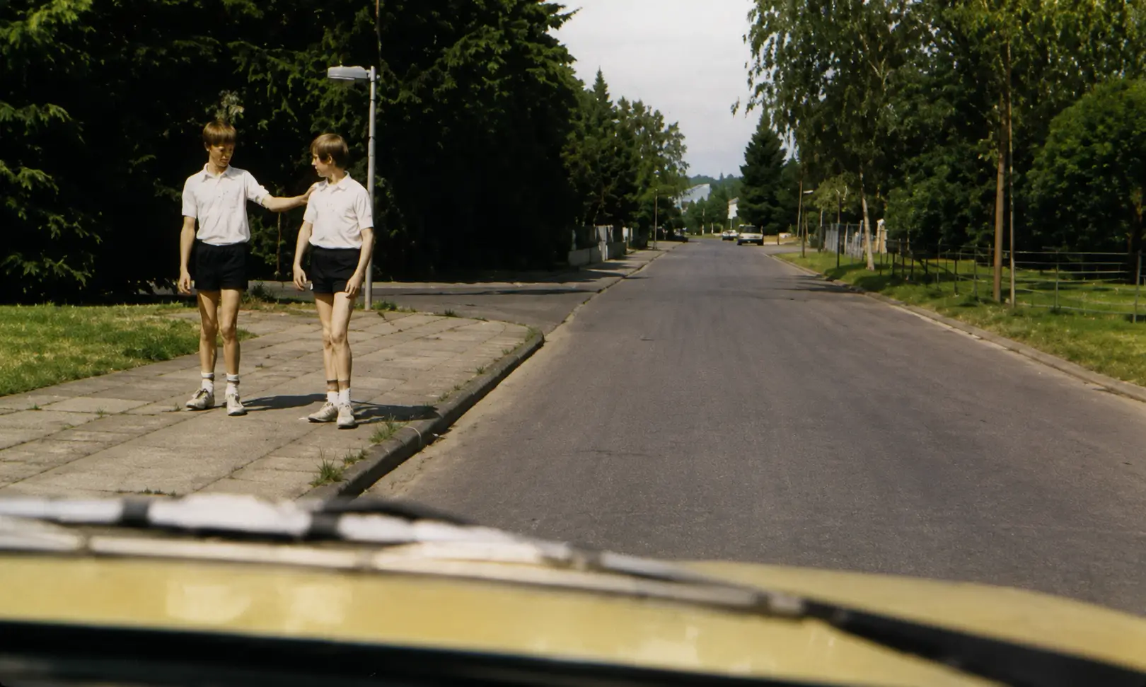 Photo of two children walking on pavement near road
