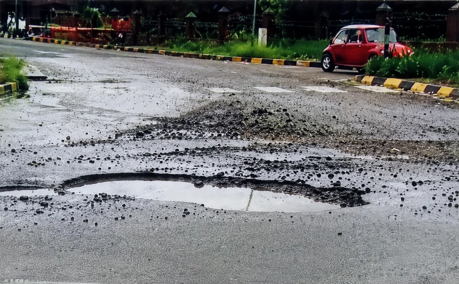 a large pothole filled with water on a wet road