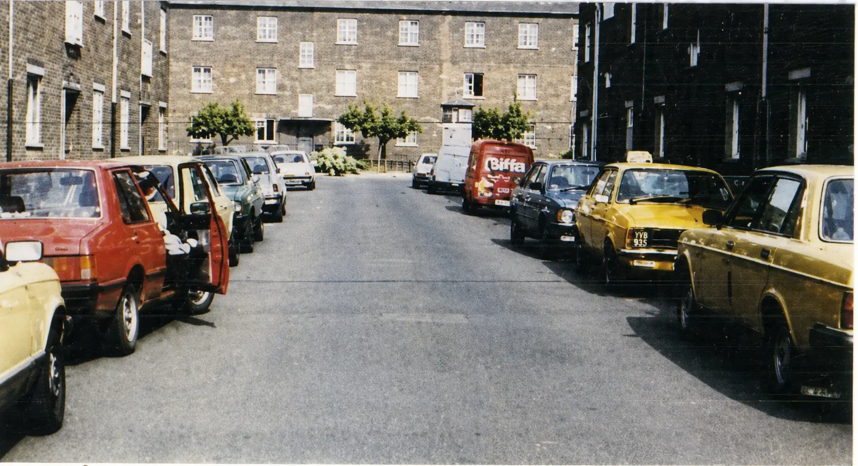 cars parked on both sides of the road in a built up area