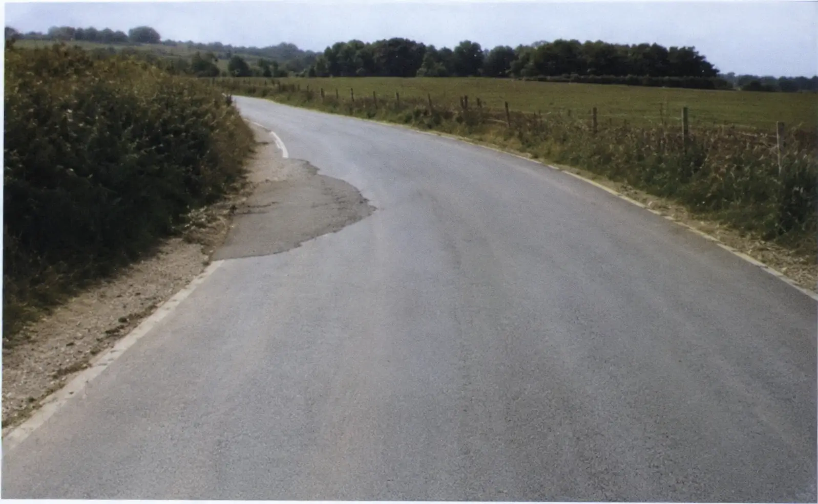 patched road surface aproaching a bend with an obscured view