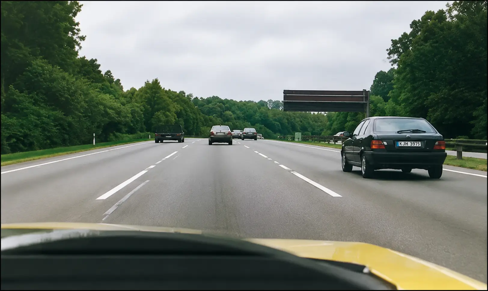 Driver's view of multi-lane highway with black car in right lane and traffic ahead